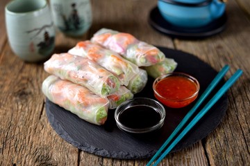 Fototapeta na wymiar Rice spring rolls - rice paper, carrots, watermelon radish, tomato, cucumber, coriander and fried shrimp. Healthy food.