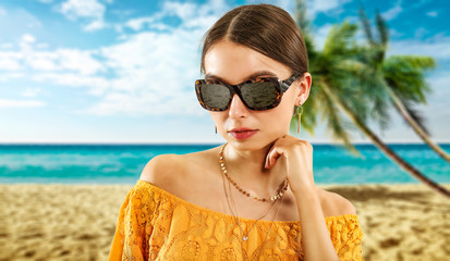 Slim young woman with sunglasses and beach landscape of palms. 