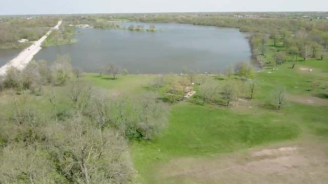 Aerial circulating around a pavilion in a public park near a small lake in rural area. Tampier Slough lake in the western suburbs of Chicago, Illinois near Lemont.
