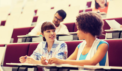 education, high school, university, learning and people concept - group of international students talking in lecture hall