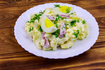 Salad with chinese cabbage, onion, sausage, eggs and mayonnaise on wooden table