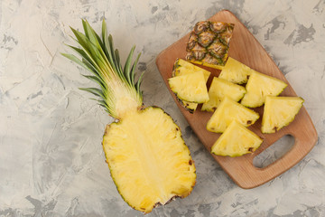 Large ripe fruit pineapple. Pineapple slices on a cutting board on a light concrete background. summer. top view.