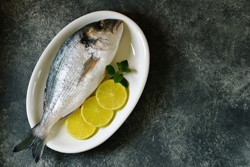 Fresh raw dorado fish with lime slices and mint leaves. Top view. Copy space. 