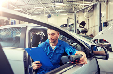 service, repair, maintenance and people concept - mechanic man with automotive diagnostic scanner...