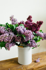 Purple bouquet of lilac flowers in a stylish vase on wooden table