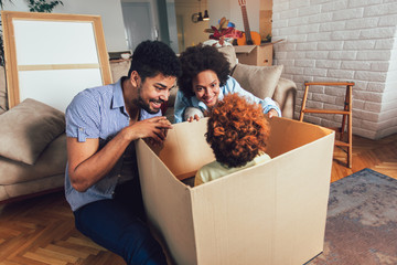 African American family, parents and daughter, unpacking boxes and moving into a new home, having fun.