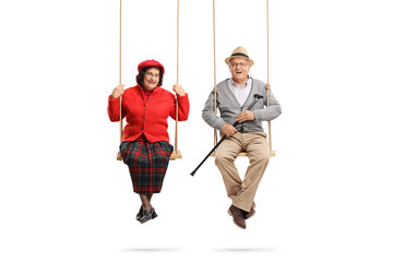 Senior man and woman sitting on swings