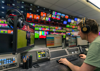 Arbeiten beim Fernsehen, Mann mit Kopfhörern vor Monitoren