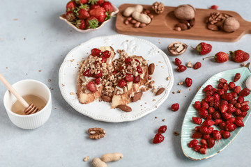 Toast crostini with fresh berries strawberries, nuts and honey, Ricotta cheese, over white board. Top view, copy space