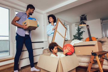 African American family, parents and daughter, unpacking boxes and moving into a new home, having fun.