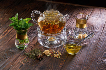 Teapot and cup of herbal tea and fresh mint on wooden table