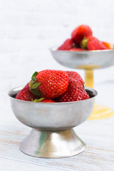 Bright ripe strawberry in a metal cups on a light background.