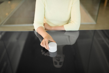 technology and people concept - close up of woman using smart speaker on black interactive panel