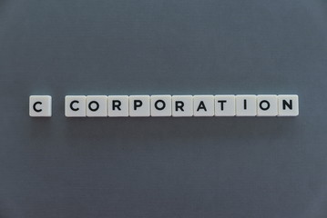 C corporation word made of square letter word on grey background.