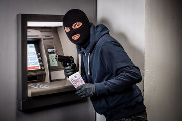 thief with a gun robs an ATM