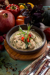 Baked chicken with grilled vegetables, greens and white sauce in pan on wooden table