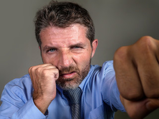 dramatic portrait of middle aged upset and fierce man boxing throwing punch looking furious suffering work stress fighting for business