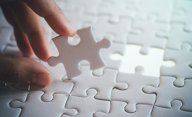last piece of white plain jigsaw holding by hand, step of success concept