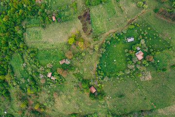 Drone view of green meadows, small houses and roads in Transylvania, Romania.