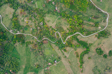 Drone view of green meadows, small houses and roads in Transylvania, Romania.