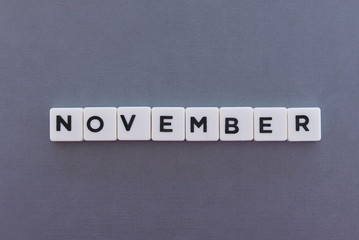 November word made of square letter word on grey background.