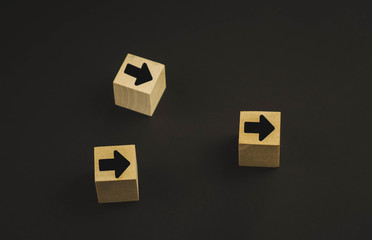 Hand putting wood cube block on top pyramid wooden blocks with red arrows facing opposite to the...