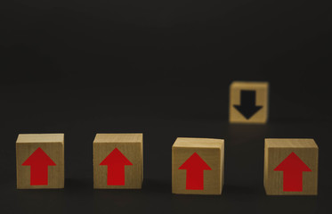 Fototapeta premium Hand putting wood cube block on top pyramid wooden blocks with red arrows facing opposite to the black arrows. With different concepts to other people. Going for success.