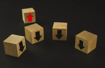 Obraz premium Hand putting wood cube block on top pyramid wooden blocks with red arrows facing opposite to the black arrows. With different concepts to other people. Going for success