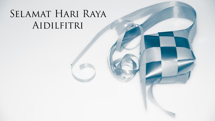 Greeting with malay word "Selamat Hari Raya Aidilfitri" that translates to wishing you a joyous hari raya on ketupat ribbon background. Selected focus. Image flare, soft, bokeh and vintage.