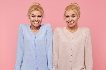 Beautiful young blonde twins confused and unable to explain and understand the current situation, shrug and smile isolated over pink background. - obrazy, fototapety, plakaty
