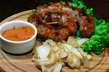 fried sausages, onions, cabbage leaf with sauce on a wooden tray