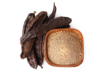 Ground carob (Ceratonia siliqua) powder with carob bean pods isolated on white background