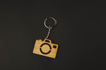 wooden trinket in the form of a camera on a black background. keychain
