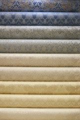 several rolls of types of wall-paper. In the wallpaper shop