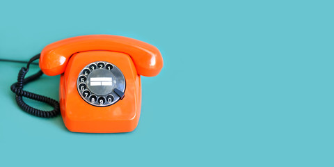 Retro phone orange color, vintage handset receiver on green background. copy space.