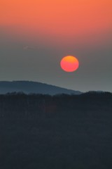 the sun sets over a hill