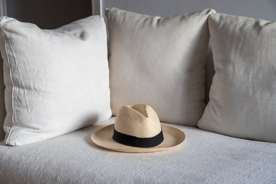 Un sombrero de paja descansa sobre un tresillo blanco con cojines