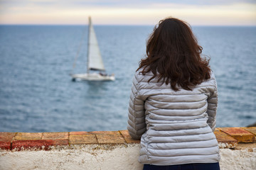 Woman looking at infinite sea and sailboat