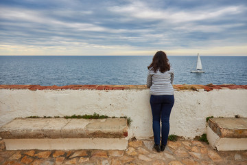 Woman looking at infinite sea and sailboat