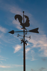 Iron weathercock in front of blue sky