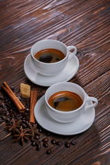 Two cups of freshly brewed espresso coffee with coffee beans on a rustic wooden table