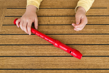 child playing and tuning red flute in a music school for education concept