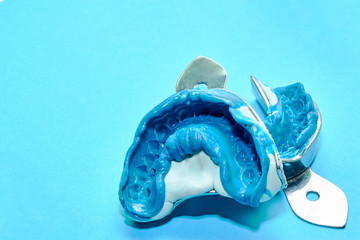 Two dental impressions on a blue background with copy space. Dental molds from the upper and lower jaws of silicone material. The imprint of the tooth row of high precision. © baklykovadaria