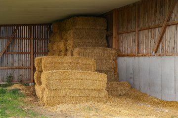 Straw bales lie under a wooden canopy