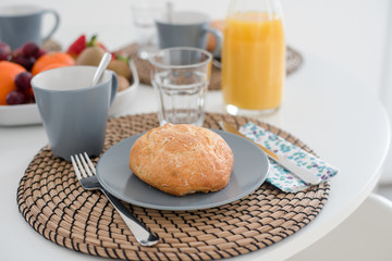 Plate with fresh crusty bread and glass of juice on grey plate