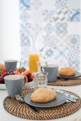 Plate with fresh crusty bread and glass of juice on white plate