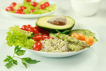 Fresh vegetarian mixed lunch with avocado, tomatoes, sprouts, asparagus and phasalis on a white background