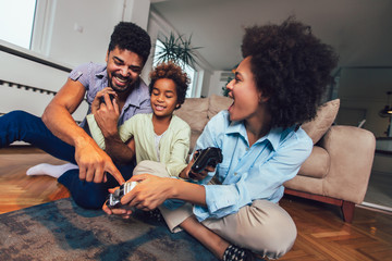 Smiling family sitting on the couch together playing video games, selective focus.