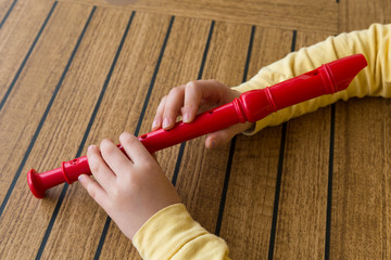 child playing and tuning red flute in a music school for education concept © Fertas