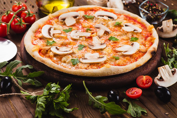 italian pizza with chicken and mushrooms on the wooden dark background (close).